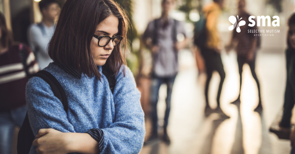 Do I have selective mutism: Woman looks down while a group converses in the background